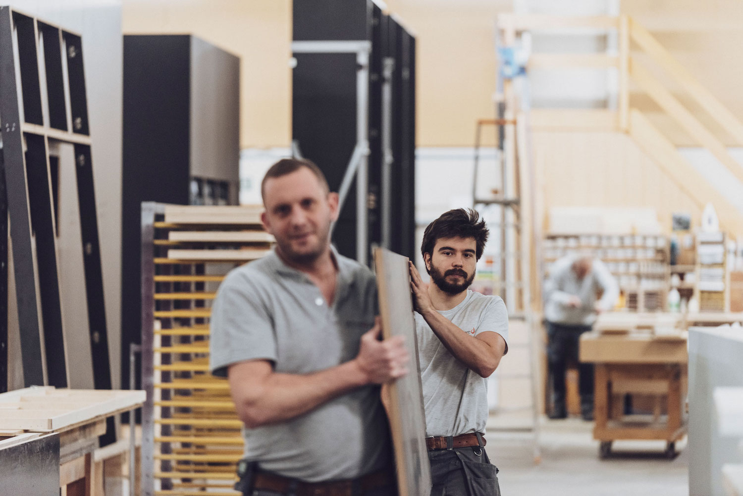 Twee medewerkers atelier De Laere Decor lopen door het atelier met plank